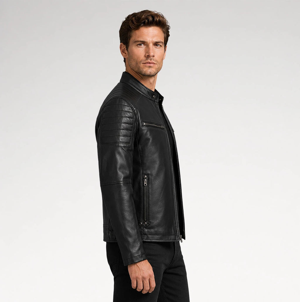 A man wearing a black leather motorcycle jacket with quilted shoulder panels and zippered details, shown in a side profile against a light gray studio background.