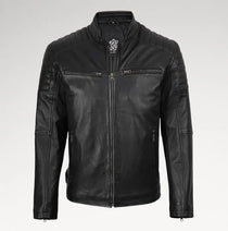 A black leather motorcycle jacket with a stand collar, quilted shoulder panels, zippered chest pockets, and a silver-toned decorative emblem on the collar, shown against a light gray background.