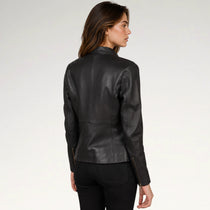 A woman shown from the back wearing a fitted black leather jacket with zip details at the cuffs, paired with black pants, against a plain light gray studio background.