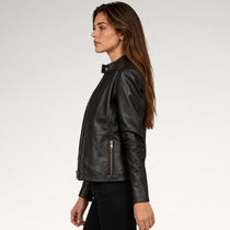 A woman shown in side profile wearing a black leather jacket with a stand collar and zippered front, photographed against a clean light gray studio background.