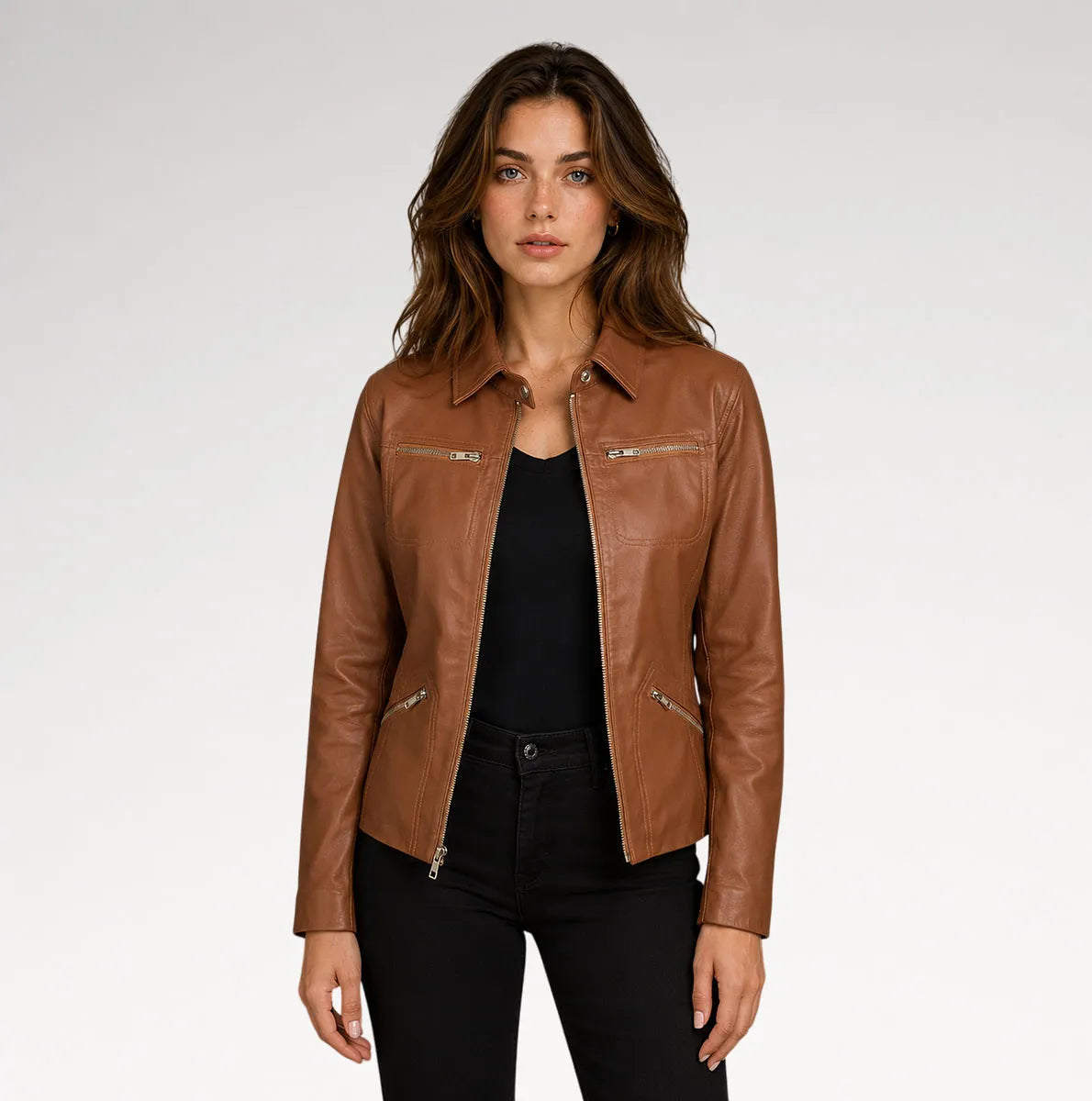 A woman modeling a brown leather moto jacket with silver zippers, worn over a black top and black jeans, against a light gray studio background. Main image