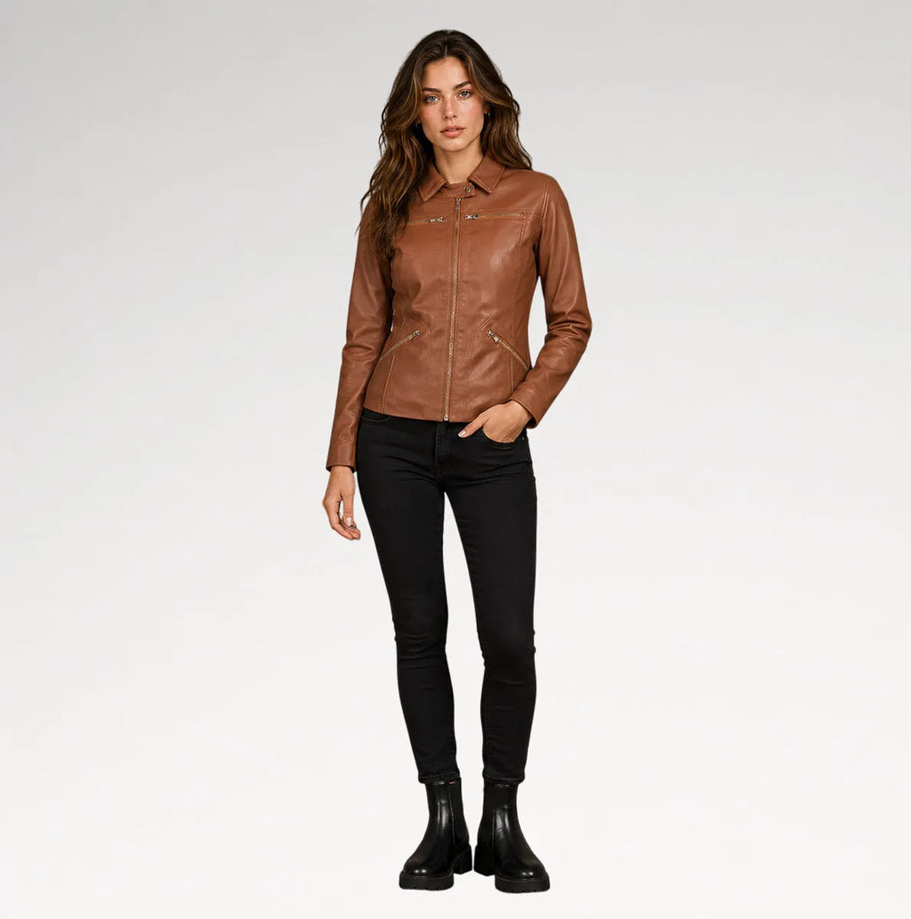 A woman modeling a brown leather jacket, black skinny jeans, and black ankle boots against a light gray studio background.