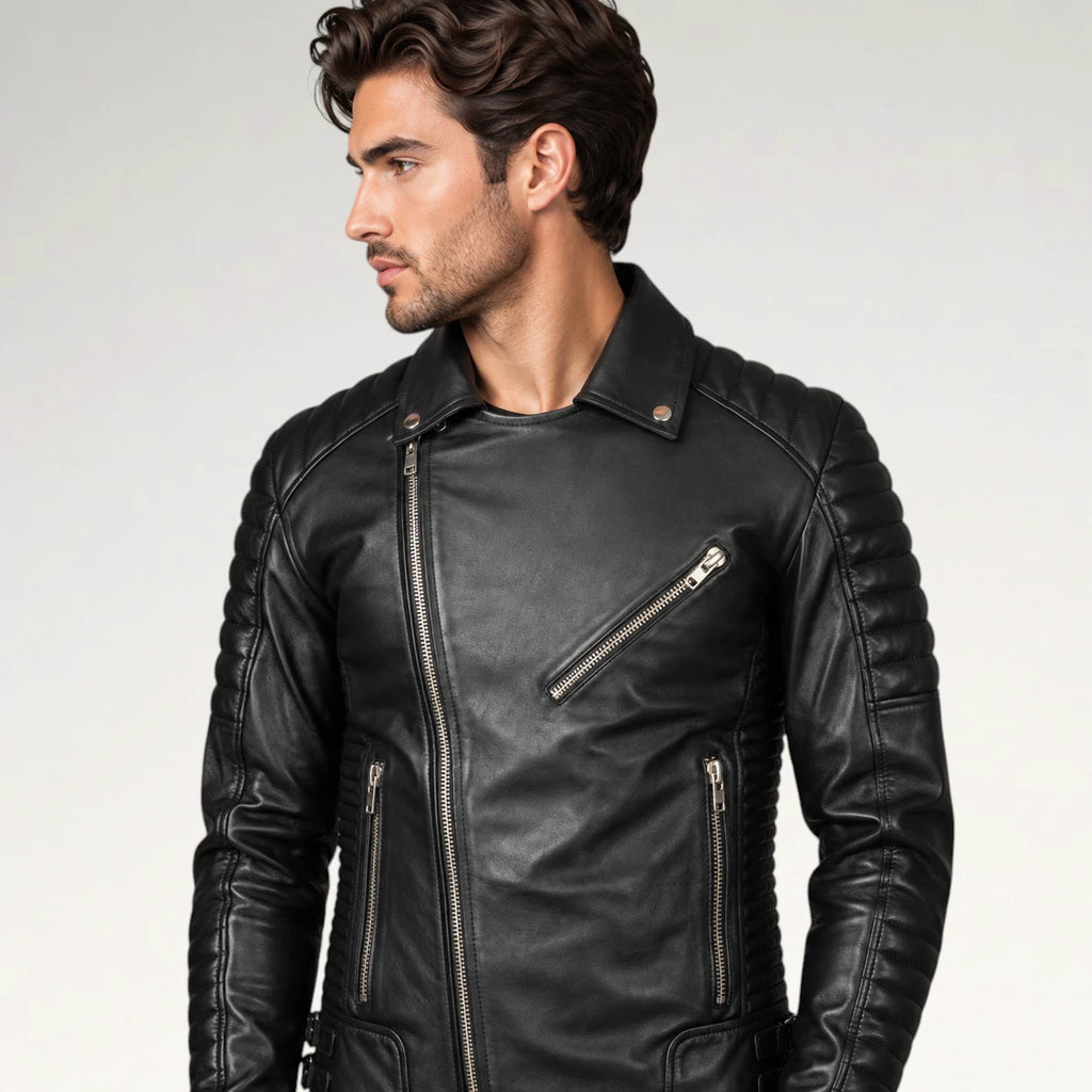 A man wearing a black leather biker jacket with silver zippers, shown from the chest up against a light gray studio background.
