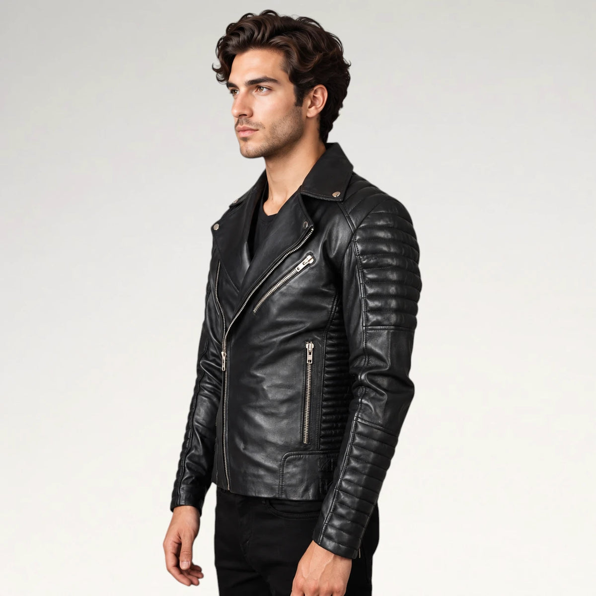 A man wearing a black leather biker jacket with silver zippers, shown in a side profile against a light gray studio background.