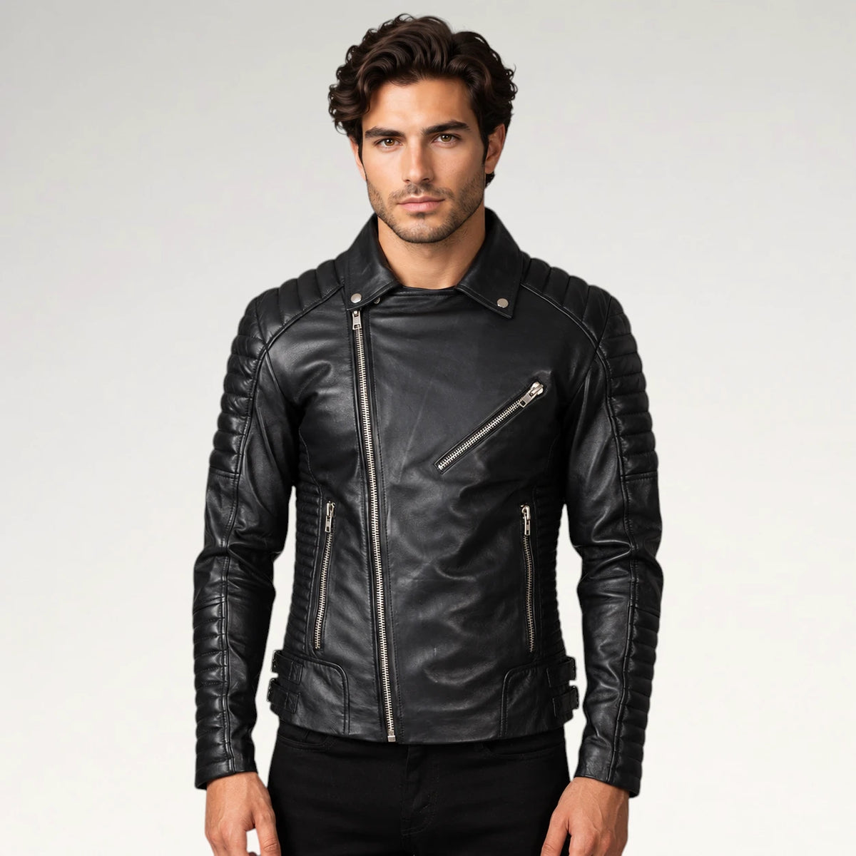 A man wearing a black leather biker jacket with silver zippers, photographed against a light gray studio background.