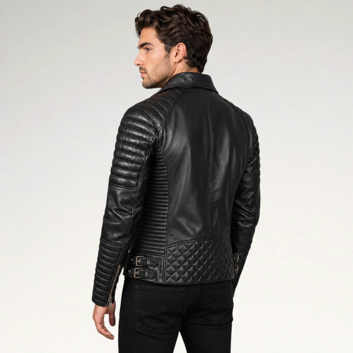 A man wearing a black leather motorcycle jacket, shown from the back and side, against a plain light gray studio background.