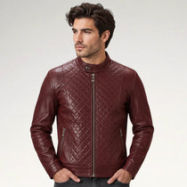 A man wearing a burgundy quilted leather jacket with a stand-up collar and front zipper, photographed against a light gray studio background.