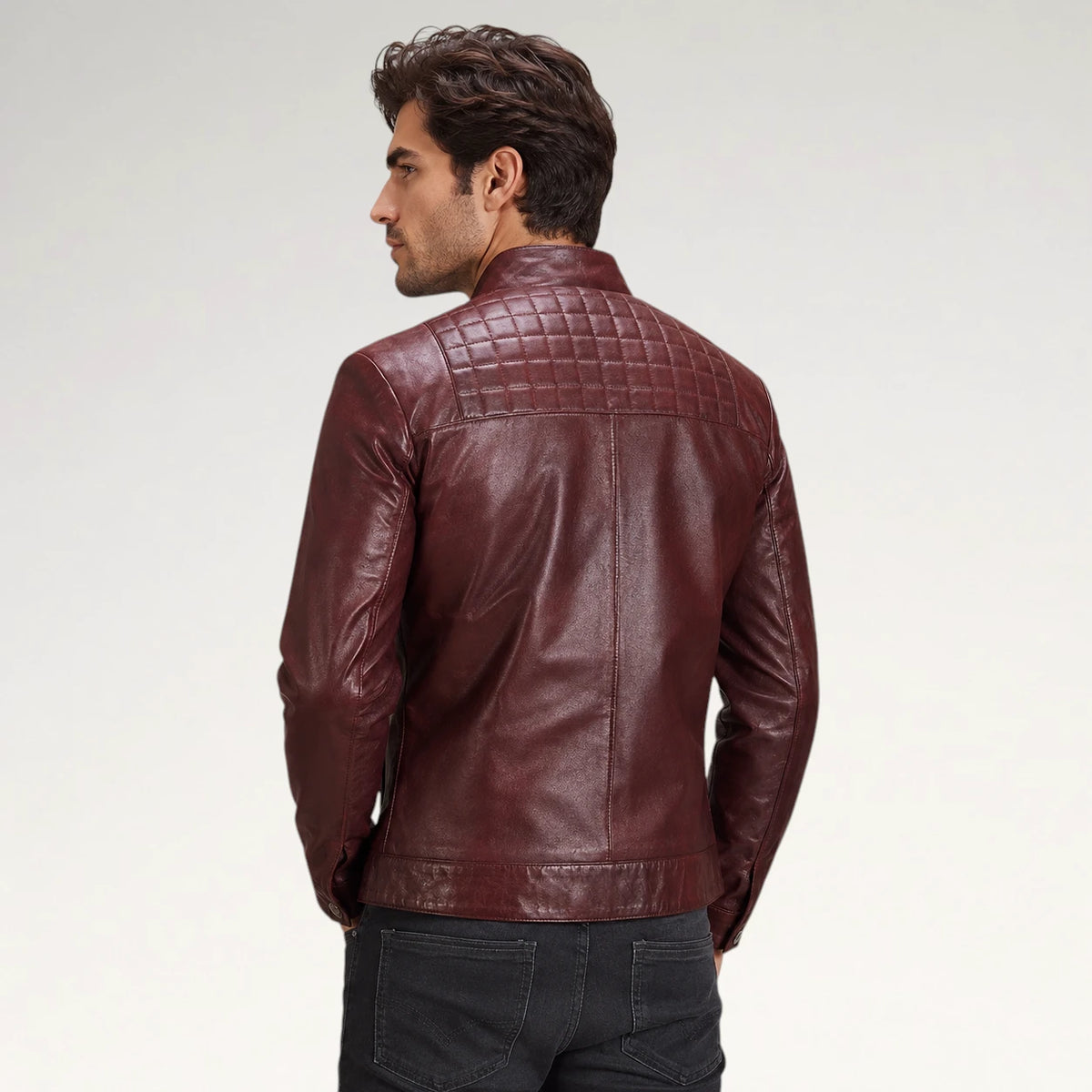 A man wearing a dark burgundy leather jacket, shown from the back against a light gray studio background.
