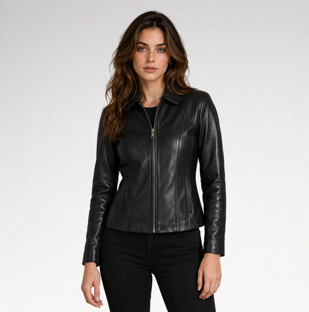 A woman modeling a black faux-leather zip-front jacket with a collar and long sleeves, paired with black pants, against a light gray studio background.