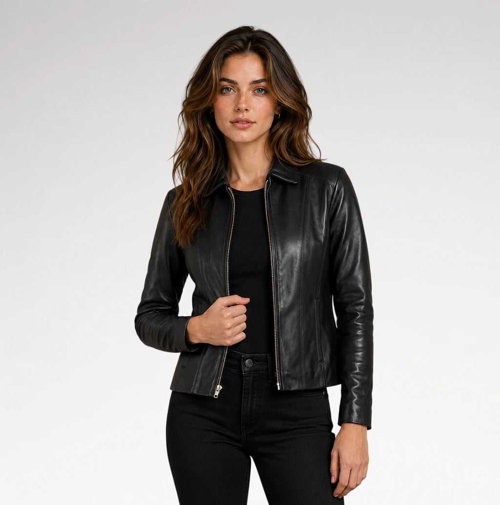 A woman modeling a black faux-leather moto jacket with silver zipper details and 'MUNICH' printed vertically on the sleeve, paired with black jeans and a black top, against a light gray studio background.