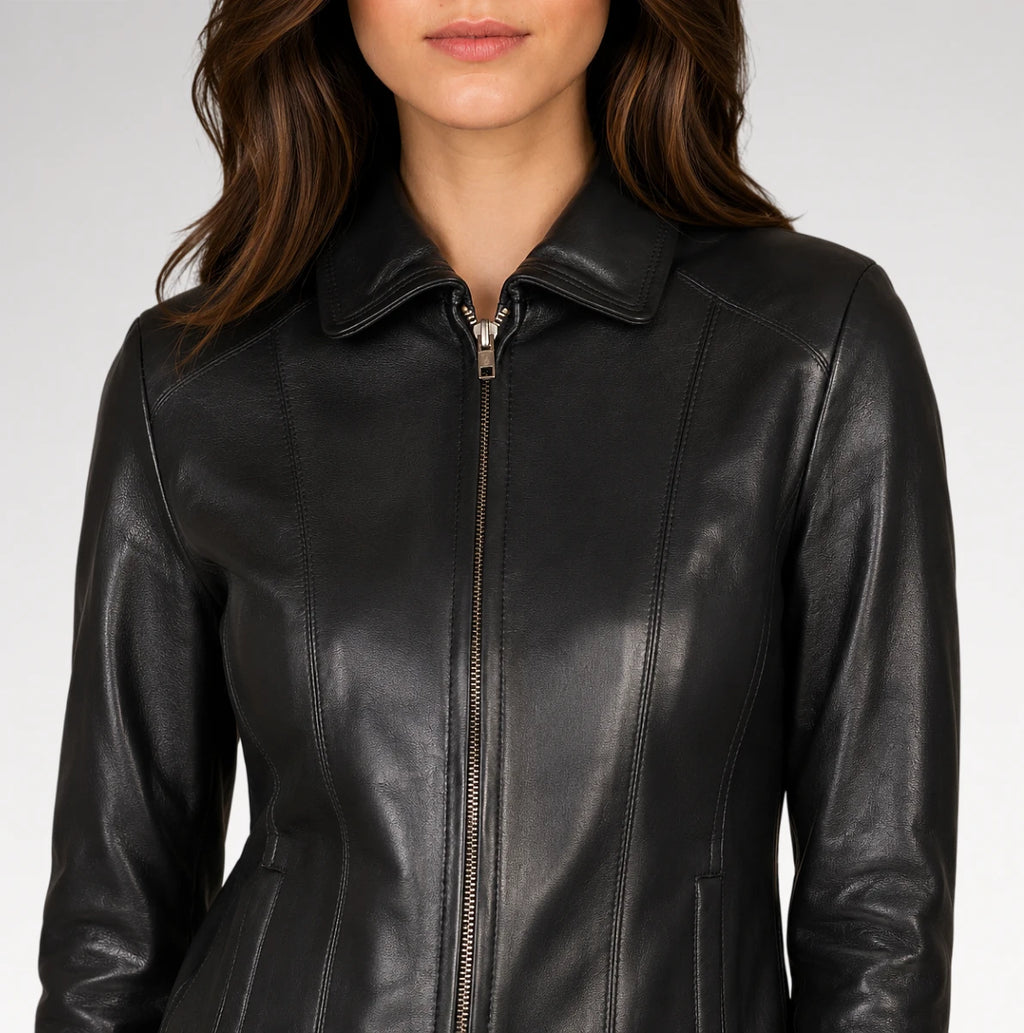 A close-up of a woman wearing a black leather jacket with a collar and front zipper, shown against a light gray studio background.