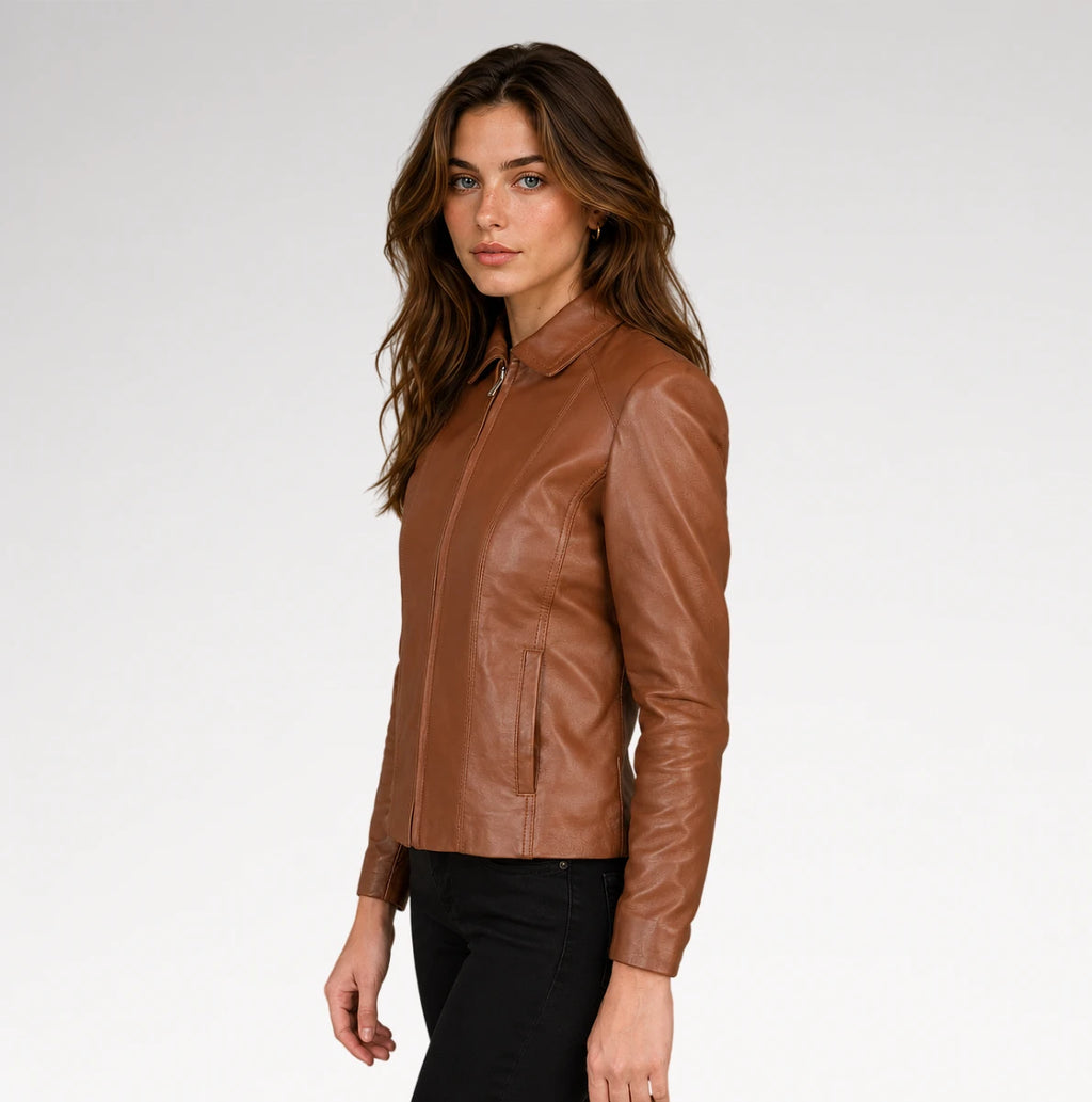 A woman modeling a brown leather jacket with a collar and front zipper, paired with black pants, against a light gray studio background.