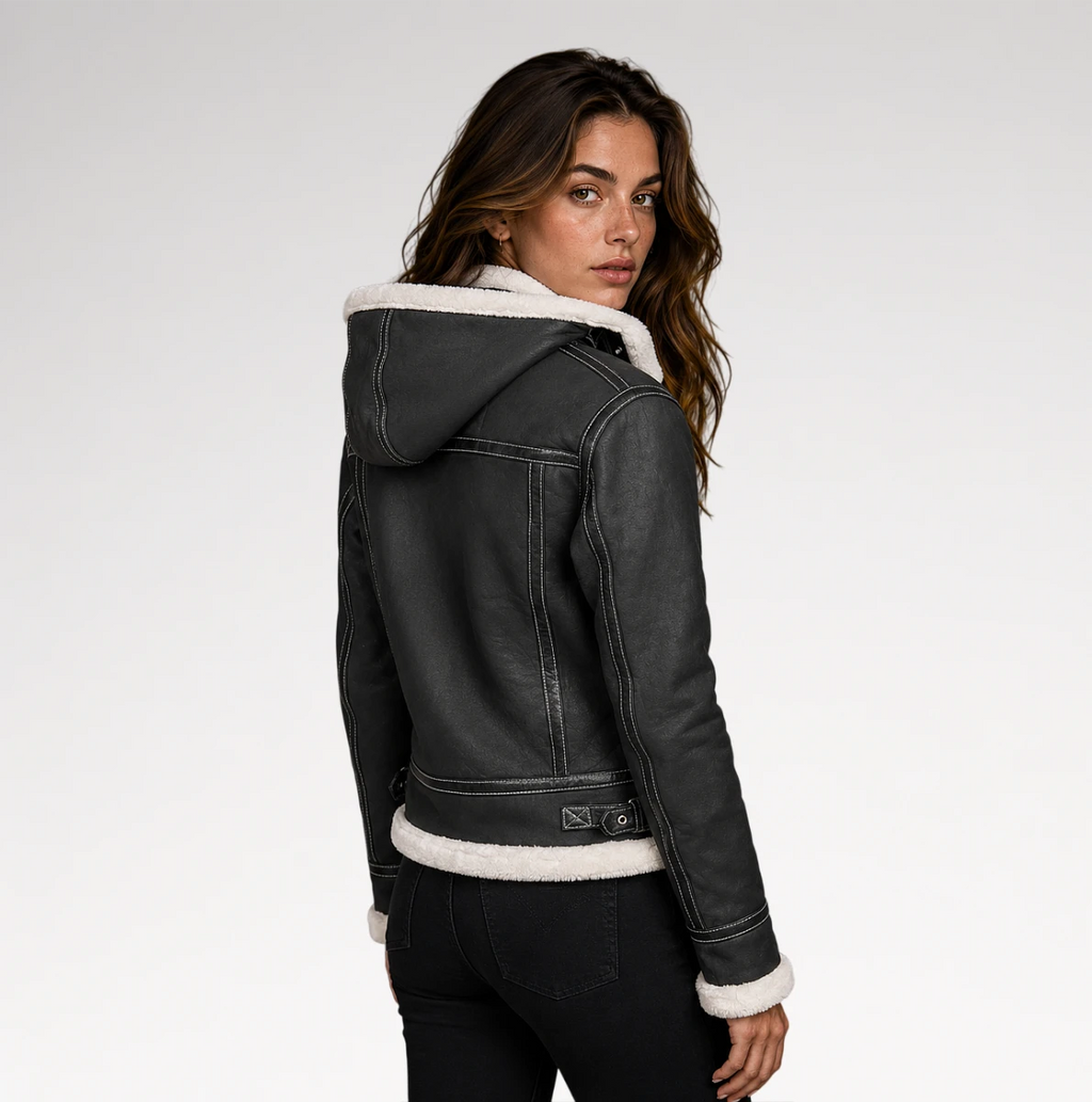 A woman wearing a dark gray hooded jacket with white shearling-style lining, photographed from the back against a light gray studio background.