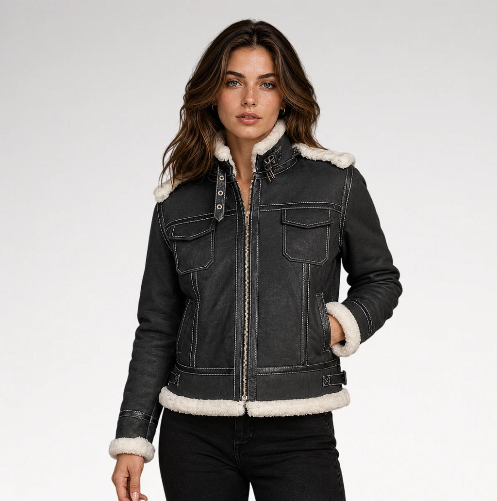 A woman modeling a dark gray denim jacket with a white shearling-style collar, hem, and cuffs, paired with black jeans against a light gray studio background.