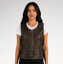 A woman wearing a dark brown distressed leather motorcycle vest over a white t-shirt and black pants, photographed against a light gray studio background.
