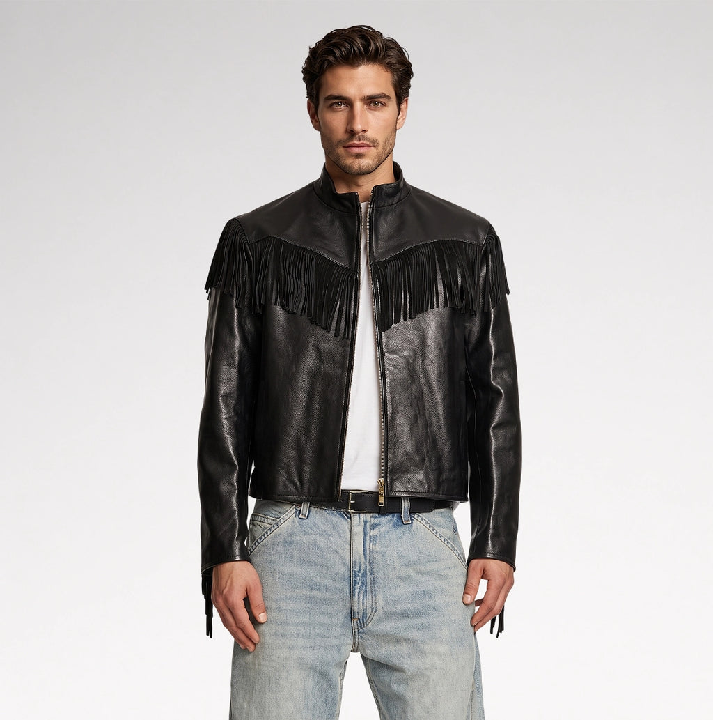 A man modeling a black leather jacket with fringe detailing across the chest, paired with a white t-shirt and light blue jeans, against a plain light gray studio background.