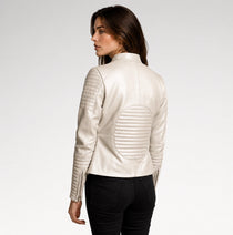 A woman shown from the back wearing a cream-colored faux leather jacket with quilted details on the shoulders and back, paired with black pants, against a light gray studio background.