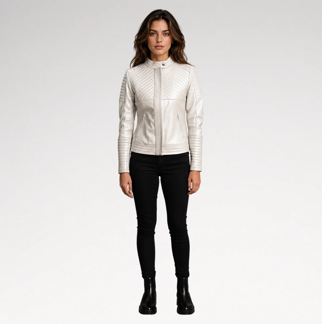 A woman modeling a white faux-leather jacket with diagonal quilted stitching on the chest and sleeves, paired with black skinny pants and black ankle boots, against a light gray studio background.