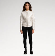 A woman modeling a white faux-leather jacket with diagonal quilted stitching on the chest and sleeves, paired with black skinny pants and black ankle boots, against a light gray studio background.