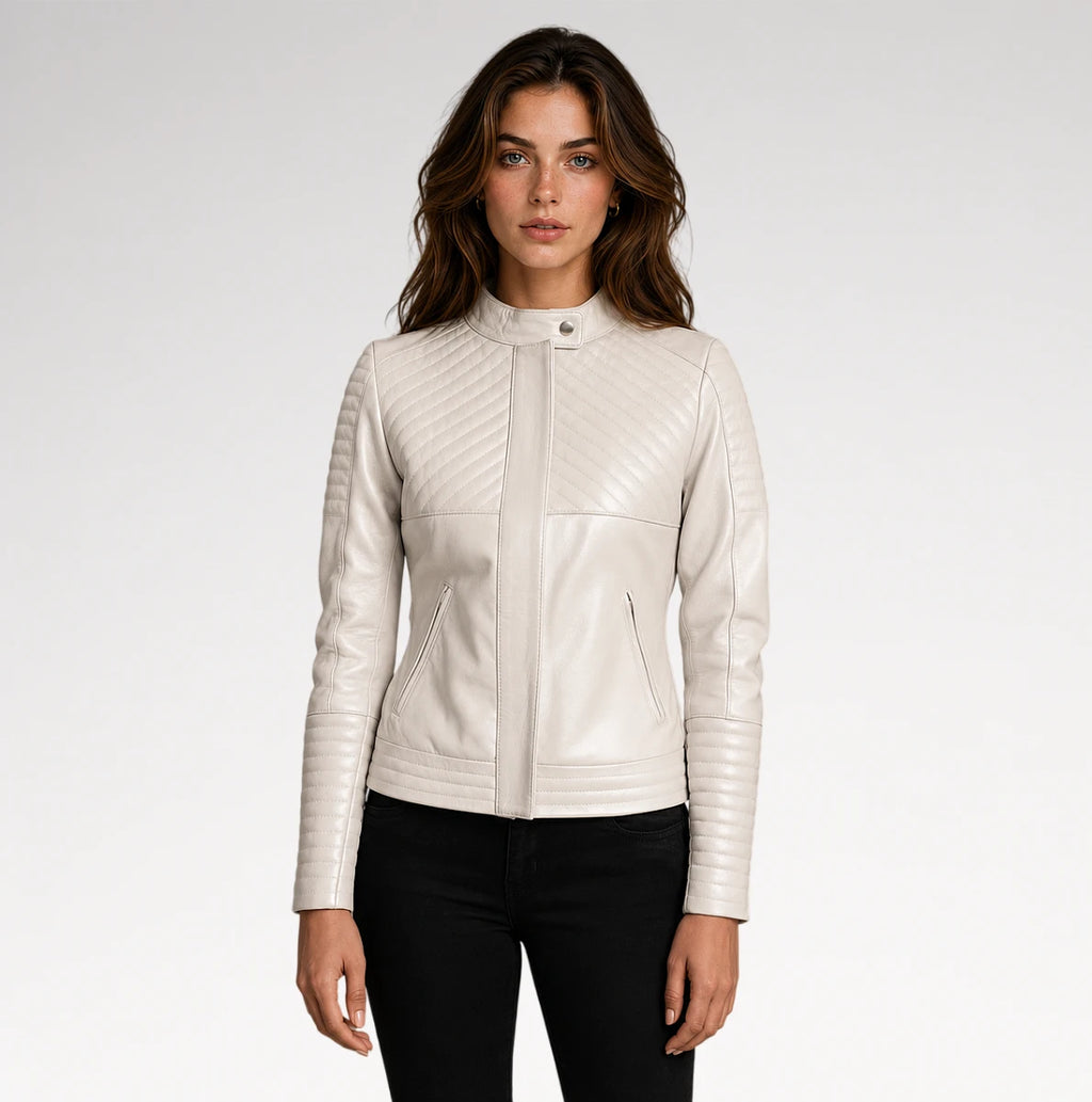 A woman modeling a cream-colored faux leather jacket with quilted diagonal stitching on the chest and sleeves, paired with black pants, against a light gray studio background.