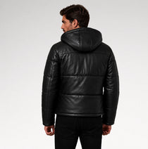 A man wearing a black puffer jacket with a hood, shown from the back against a light gray studio background.