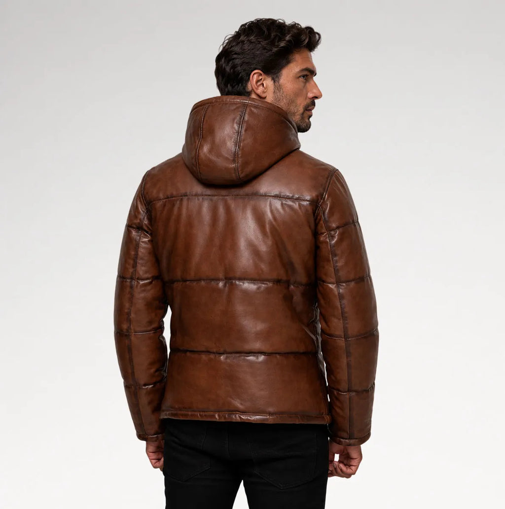 A man wearing a brown quilted leather jacket with a hood, shown from the back against a light gray studio background.