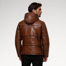 A man wearing a brown quilted leather jacket with a hood, shown from the back against a light gray studio background.