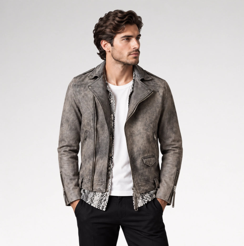 A man wearing a distressed gray faux-leather moto jacket over a white t-shirt and black pants, standing against a light gray studio background.