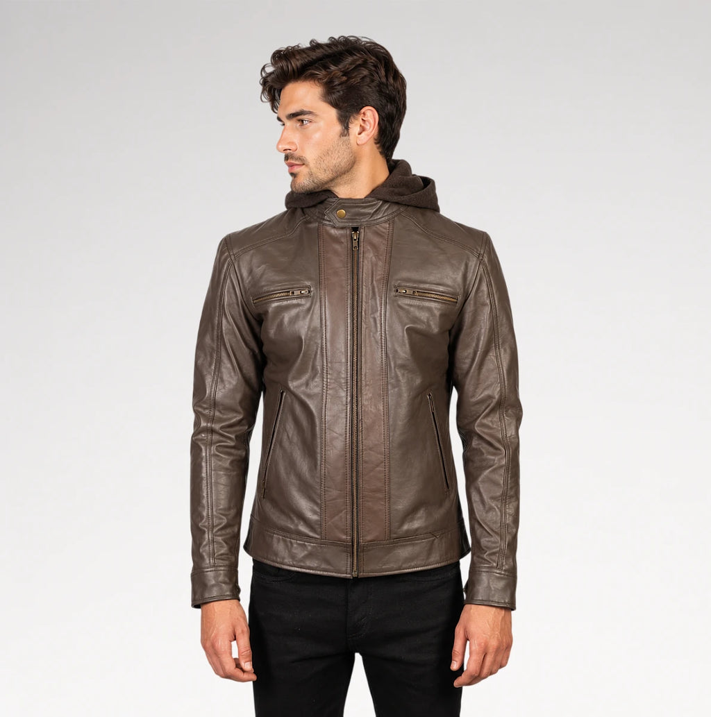 A man wearing a brown leather hooded jacket with zippered chest pockets, shown from the waist up against a light gray studio background.