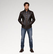 A man modeling a dark brown leather jacket with a stand collar and button front, paired with blue jeans and brown leather shoes, against a light gray studio background.