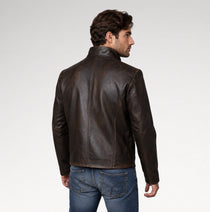 A man wearing a dark brown leather jacket, shown from the back and side profile against a light gray studio background.