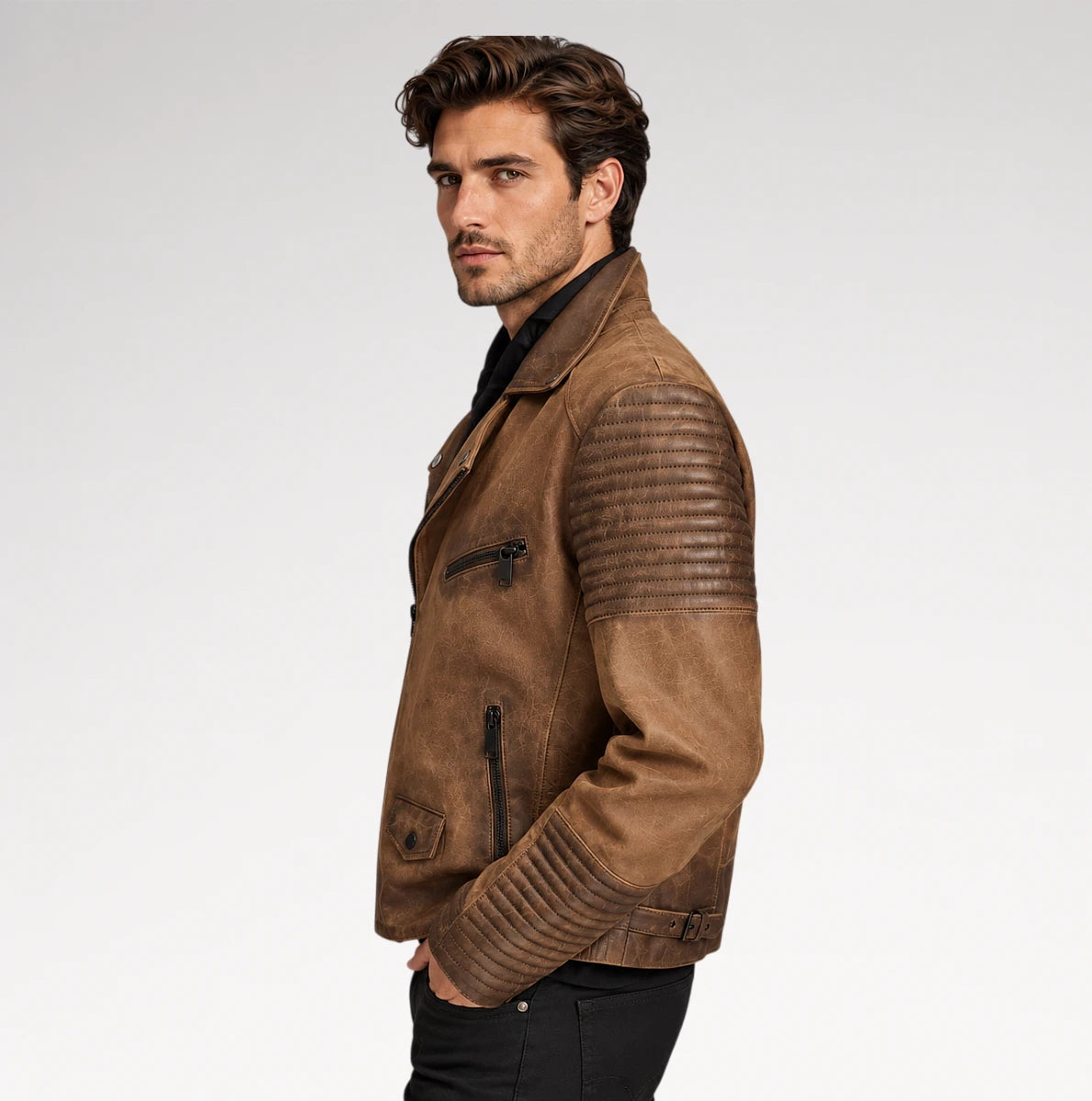 A man wearing a brown suede motorcycle jacket with quilted shoulder panels, shown in profile against a light gray studio background.
