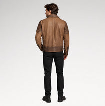 A man viewed from the back wearing a brown leather jacket with textured sleeve panels, black pants, and black boots, photographed against a clean white studio background.