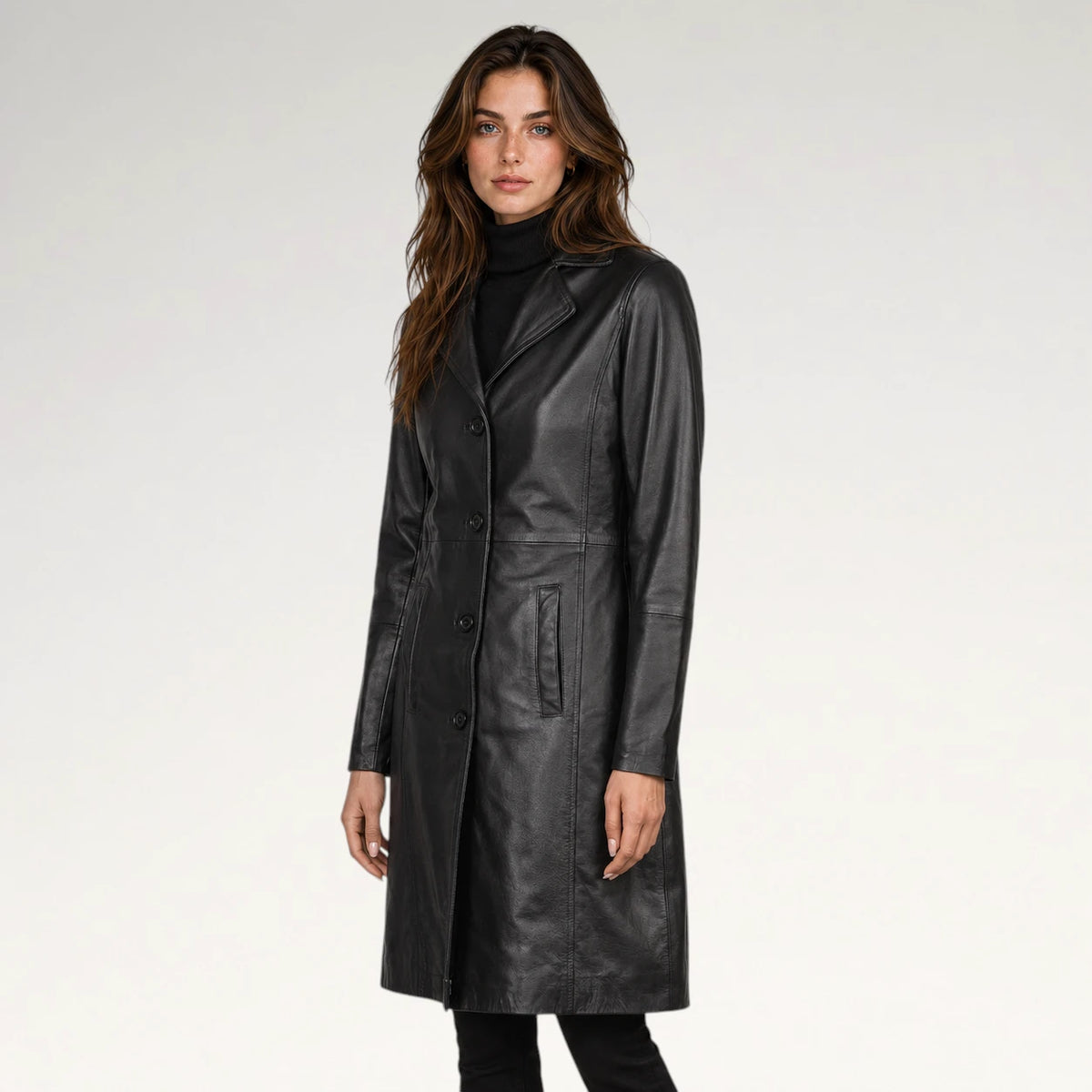 A woman modeling a black leather coat over a black turtleneck sweater, photographed against a clean light gray studio background.