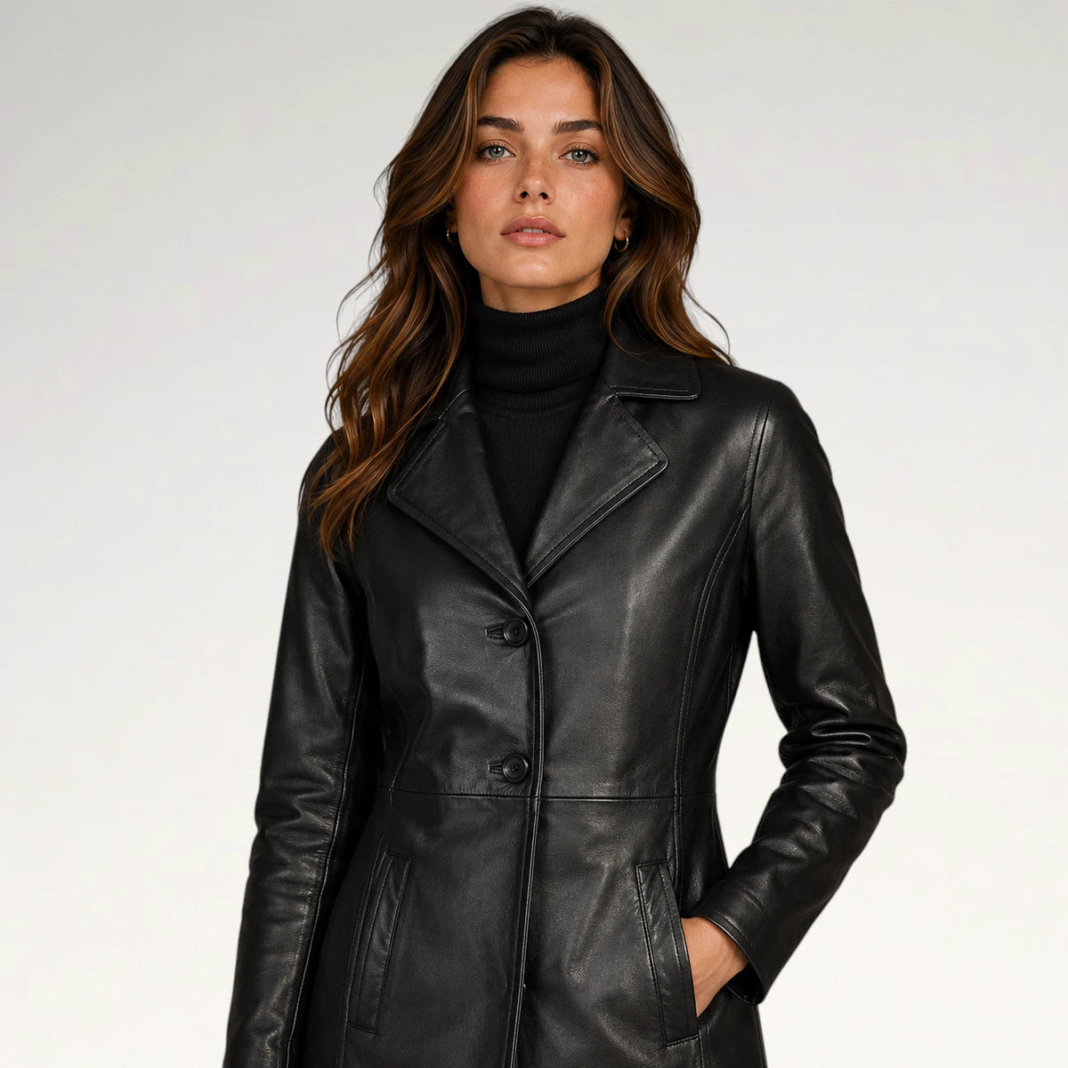A woman wearing a black leather coat over a black turtleneck sweater, photographed against a clean light gray studio background.