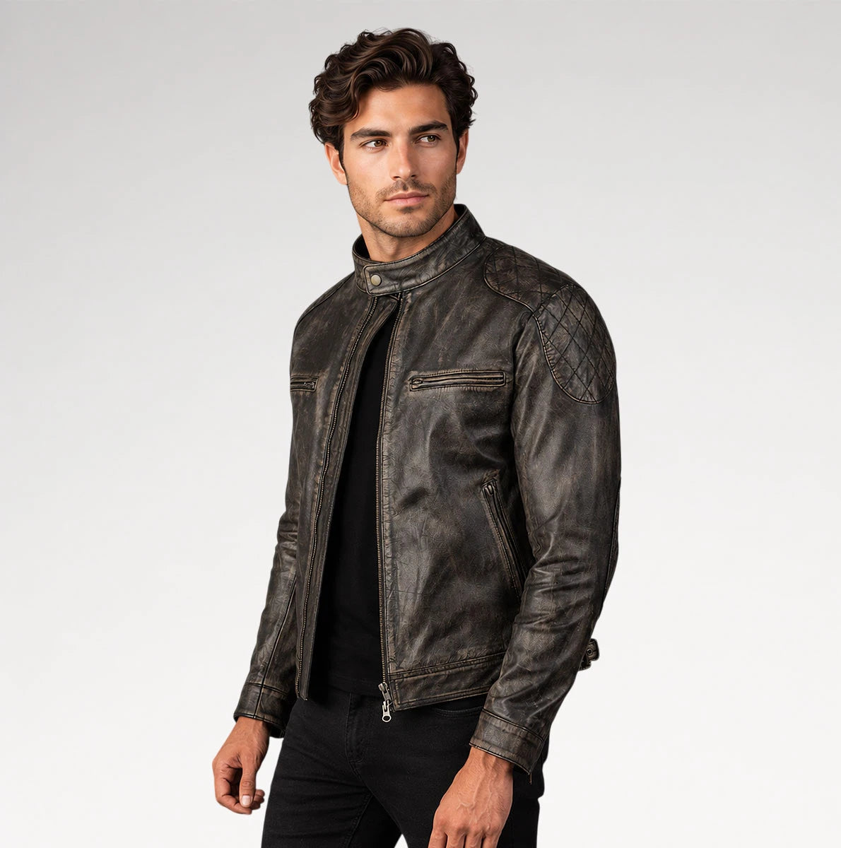 A man wearing a distressed dark brown leather motorcycle jacket over a black shirt and black pants, photographed against a light gray studio background.