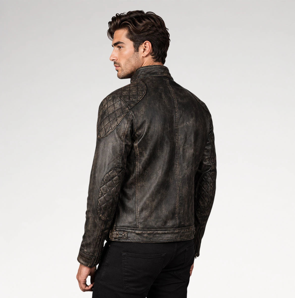 A man wearing a dark distressed leather jacket with quilted shoulder and sleeve panels, shown from a three-quarters back view against a light gray studio background.