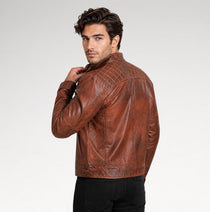 A man wearing a brown leather jacket with embossed geometric patterns on the shoulders and back, shown from a three-quarter back view against a light gray studio background.