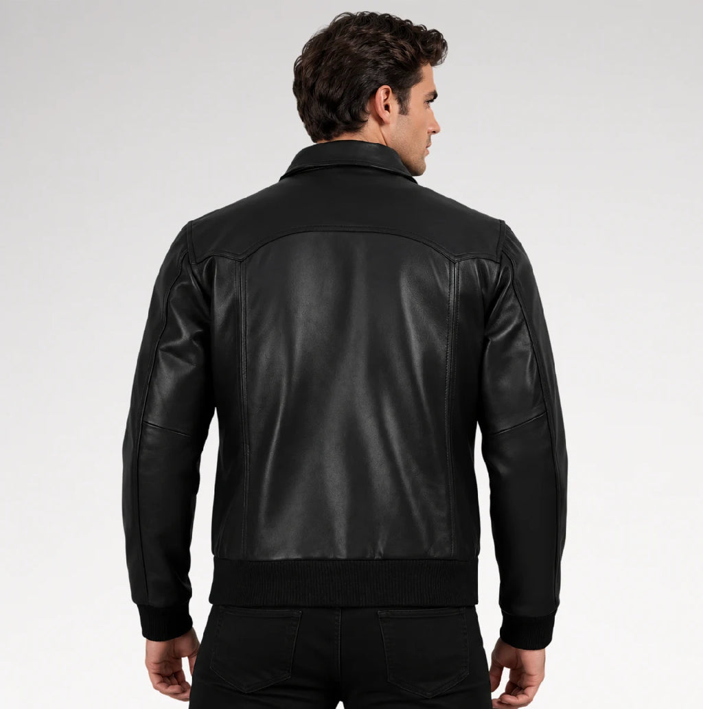 A man viewed from the back wearing a black leather jacket with ribbed knit collar, cuffs, and hem, set against a plain light gray studio background.