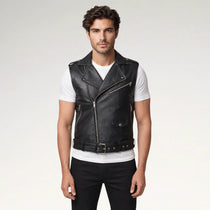 A man modeling a black faux-leather biker vest with silver zippers and a matching belt, worn over a white t-shirt and black pants against a light gray background.