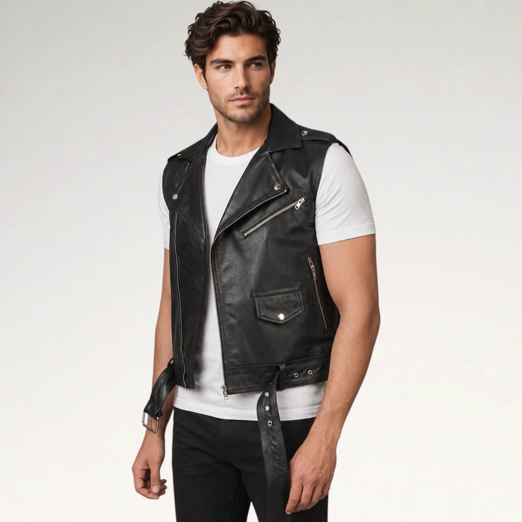 A man wearing a black leather motorcycle vest over a white t-shirt and black pants, standing against a light gray studio background.