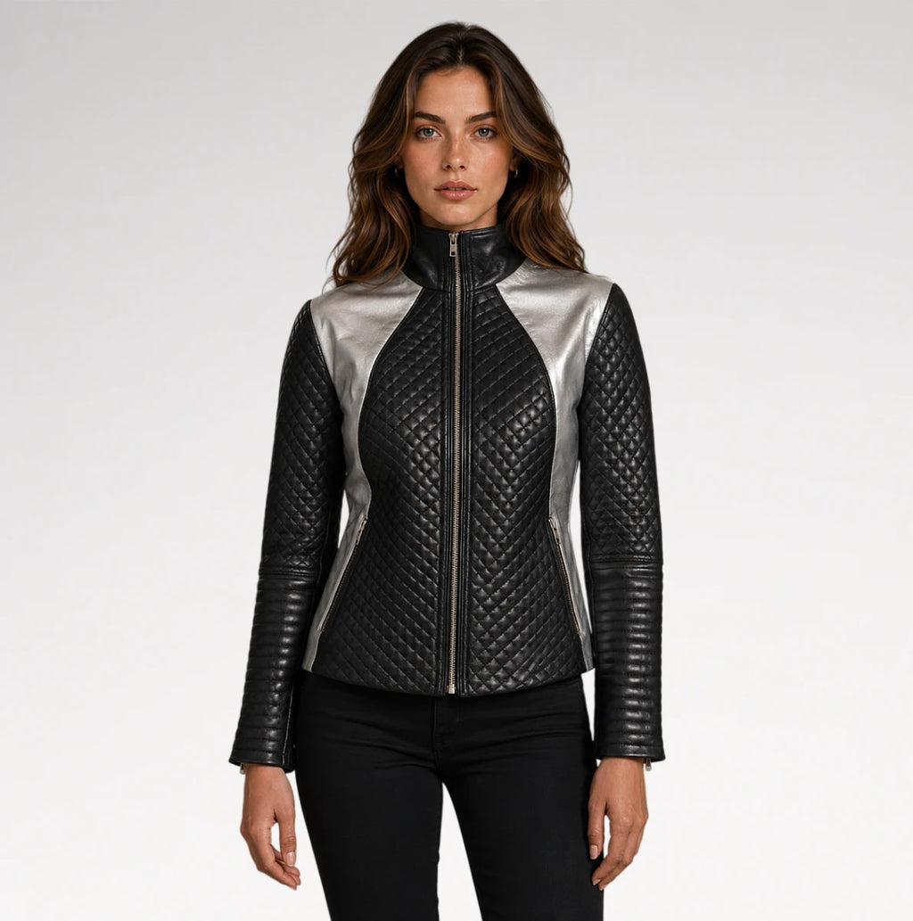 A woman modeling a black quilted faux-leather jacket with metallic silver side panels and a silver front zipper, paired with black pants against a light gray studio background.