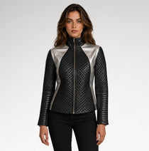 A woman modeling a black quilted faux-leather jacket with metallic silver side panels and a silver front zipper, paired with black pants against a light gray studio background.