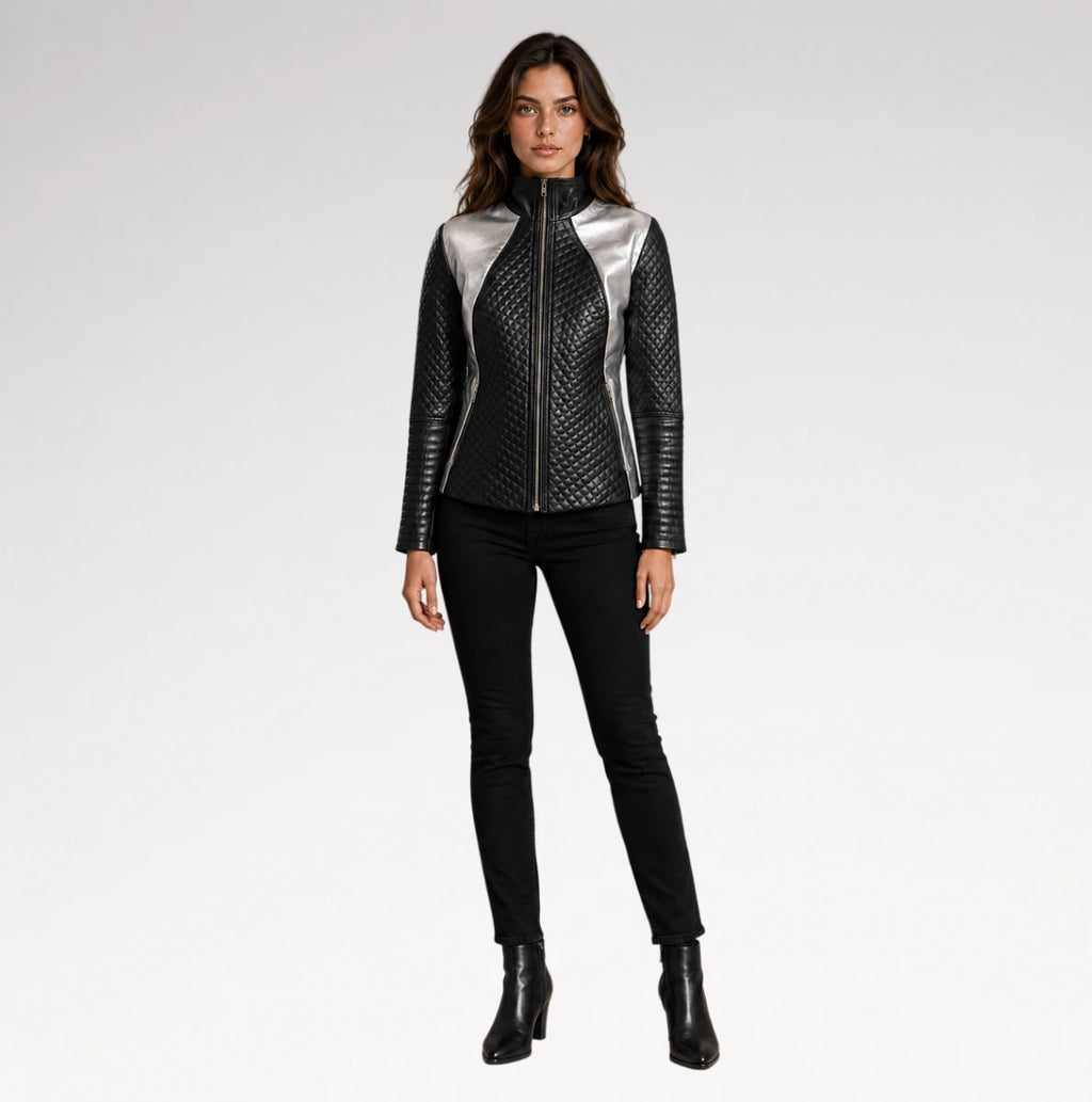 A model stands against a light gray studio background wearing a black quilted faux-leather jacket with metallic silver shoulder panels, black skinny pants, and black ankle boots.