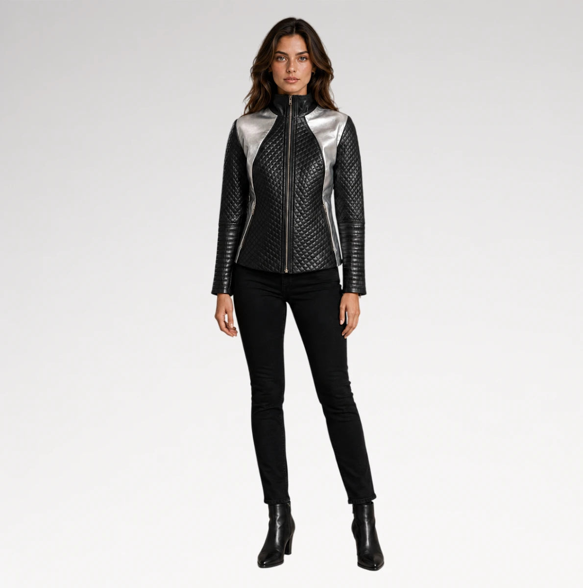 A model stands against a light gray studio background wearing a black quilted faux-leather jacket with metallic silver shoulder panels, black skinny pants, and black ankle boots.