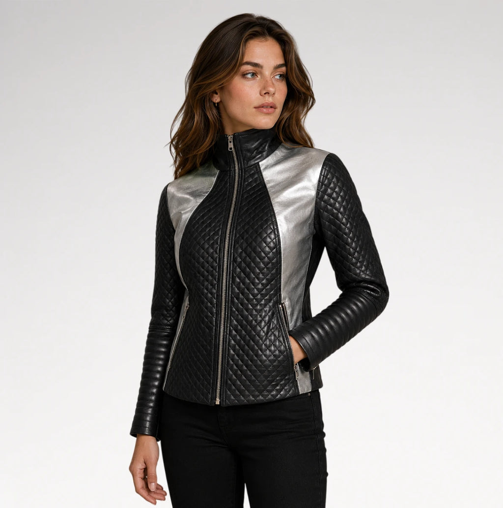 A woman shown from the back wearing a black leather jacket with quilted sleeves and a high collar, paired with black pants, against a plain light gray studio background.