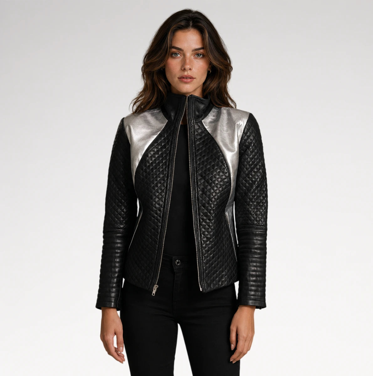 A woman modeling a black quilted leather jacket with metallic silver shoulder panels, styled with a black top and black pants against a light gray studio background.