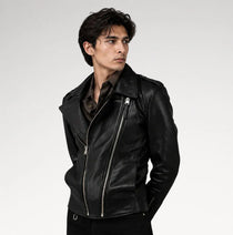 A man wearing a black leather motorcycle jacket with silver zippers, posed against a light gray studio background.