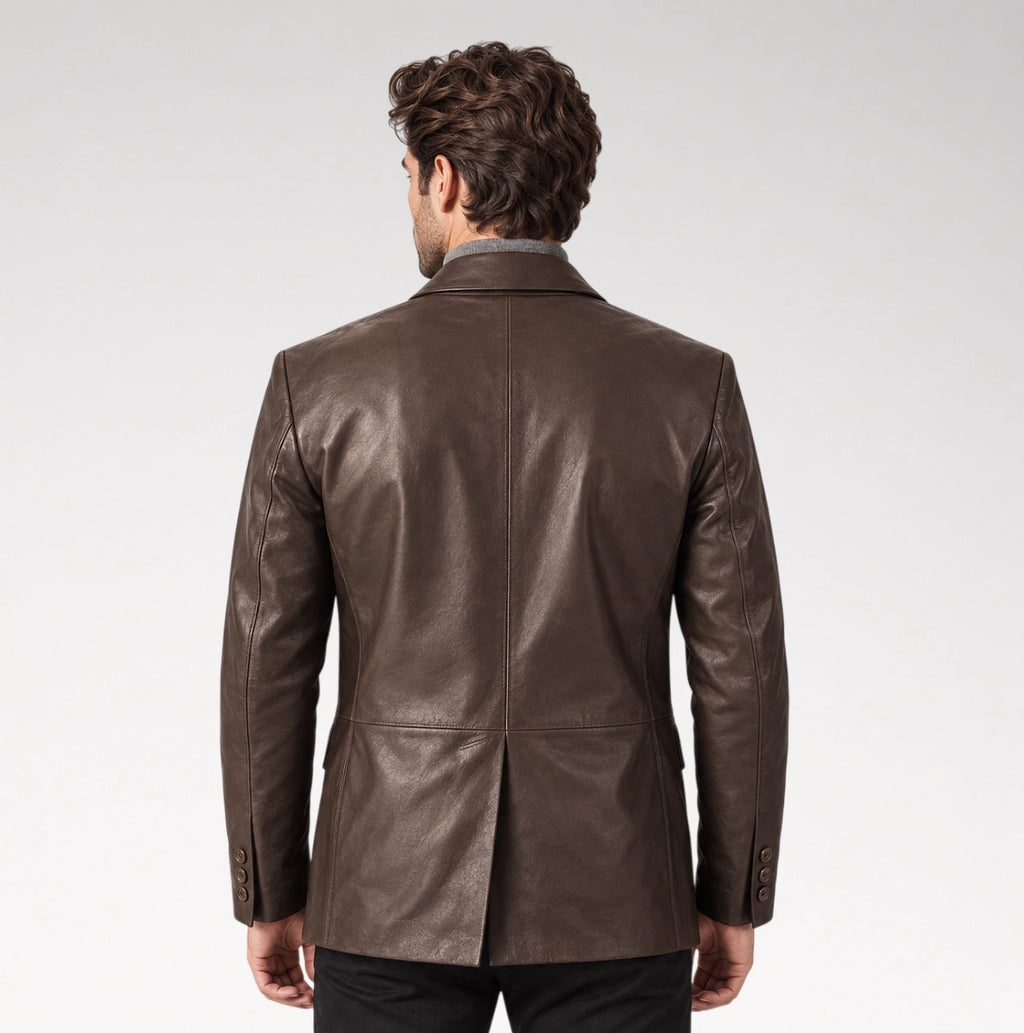 A man viewed from behind wearing a dark brown leather blazer over a collared shirt, set against a plain light gray studio background.