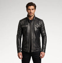 A man wearing a black leather jacket with contrasting white stitching and zippered chest pockets, photographed against a light gray studio background.